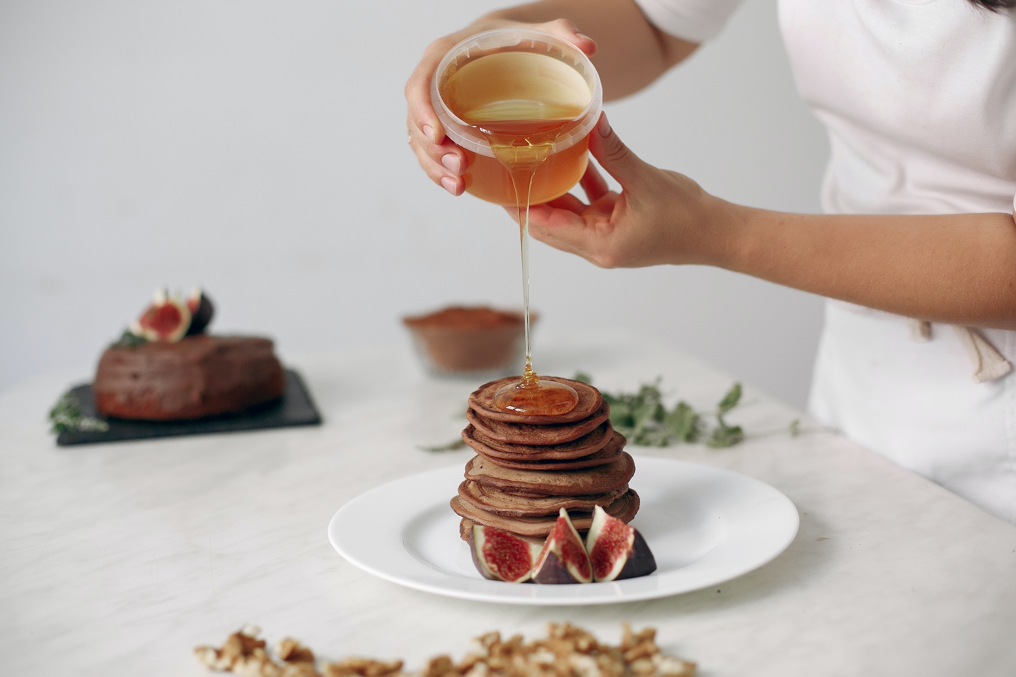 Cook pours honey on the pancakes.