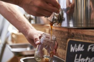 Man Filling Container With Wild Honey In Sustainable Plastic Free Grocery Store